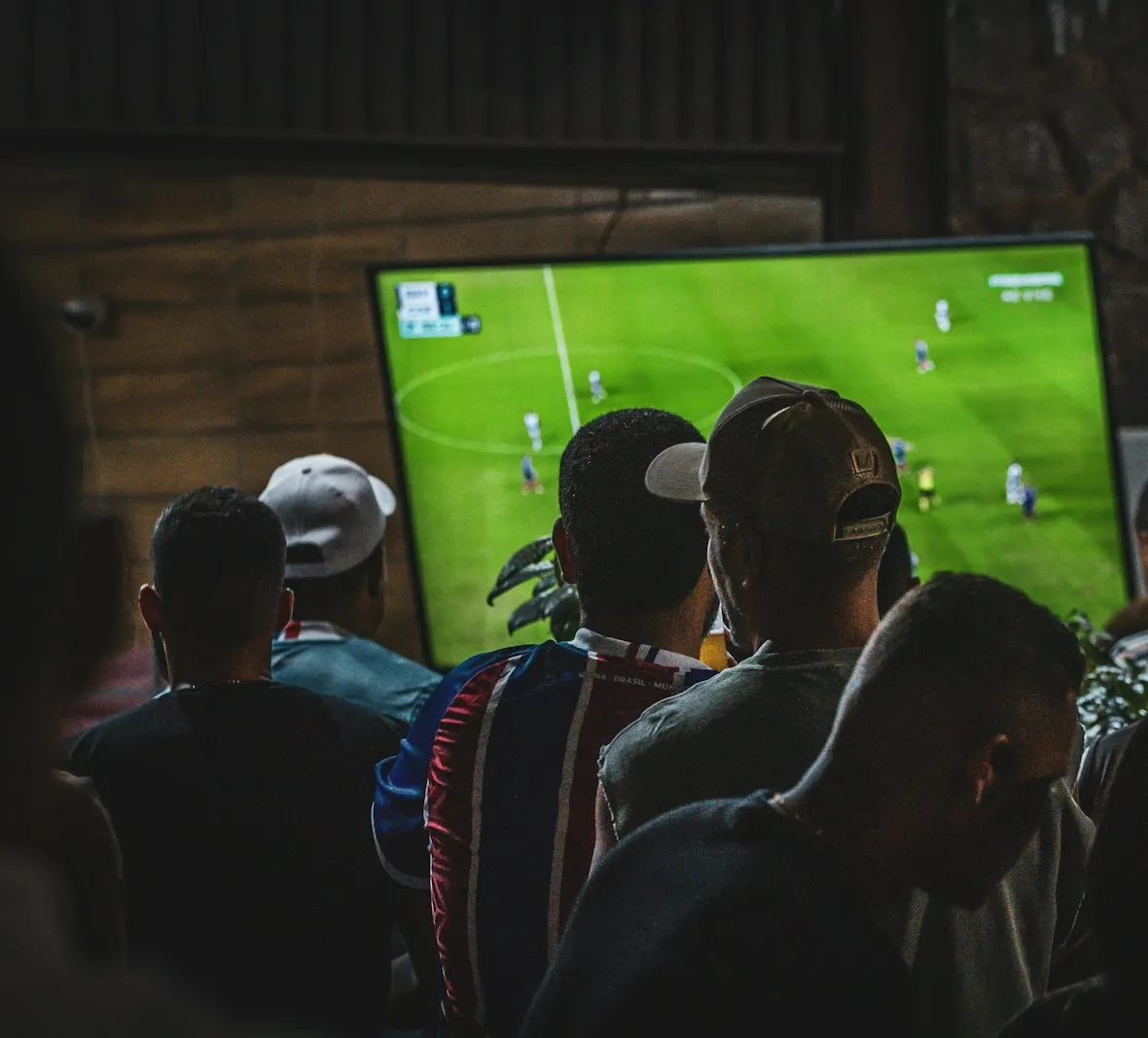 Folk i en bar ser en fotballkamp på storskjerm